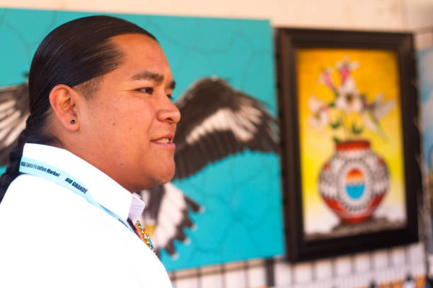 2017 Santa Fe Indian Market: Pueblo Painter with Paintings Santa Fe, NM, USA: Artist Jason Valencia from San Felipe Pueblo with his paintings at the 2017 Santa Fe Indian Market. The market, now in its 96th year, is spread out around the historic Santa Fe Plaza, showcasing North American Indigenous arts and culture. More than 900 artists from hundreds of tribes participate in the two-day event; visitors number about 100,000. puebloan peoples stock pictures, royalty-free photos & images