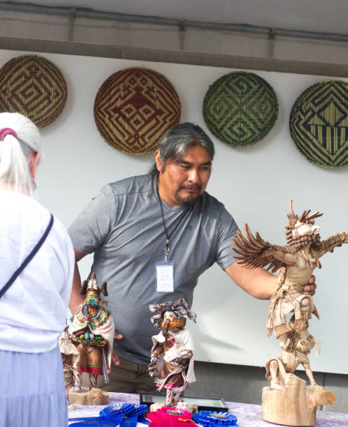 2017 Santa Fe Indian Market: Hopi Sculptor with Kachina Dolls Santa Fe, NM, USA: Hopi artist Arthur Holmes with his carved Kachina dolls at the 2017 Santa Fe Indian Market. The market, now in its 96th year, is spread out around the historic Santa Fe Plaza, showcasing North American Indigenous arts and culture. More than 900 artists from hundreds of tribes participate in the two-day event; visitors number about 100,000. kachina doll stock pictures, royalty-free photos & images
