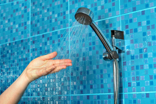 Latino woman in her 30s taking a hot shower in the bathroom of her home. Hot water from the shower to the hands
