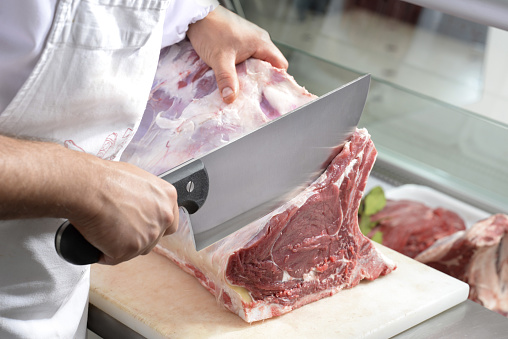 Man cuts beef meat in the kitchen