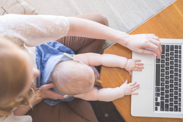 istock Mom works on her computer while holding her infant baby in her lap 836323158