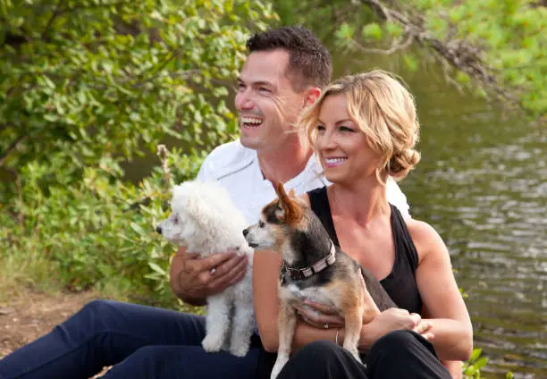 Photo of beautiful couple with dogs at lake