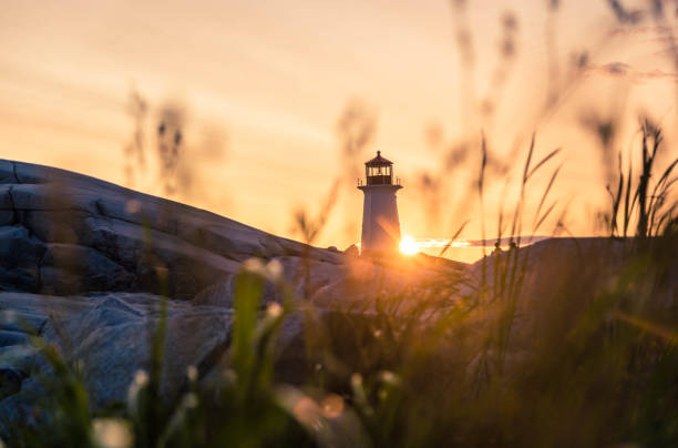 Lighthouse at sunset Lighthouse at sunset on the East Coast of Canada peggys cove stock pictures, royalty-free photos & images