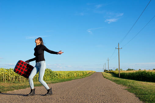 Young smiling woman hitchhiking on the road