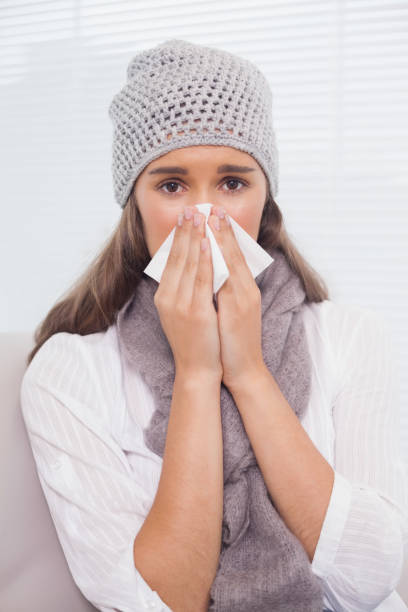 istock Pretty brunette with winter hat on blowing her nose 836347012
