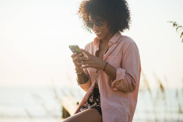 istock Millennial black woman using phone at beach 836350656