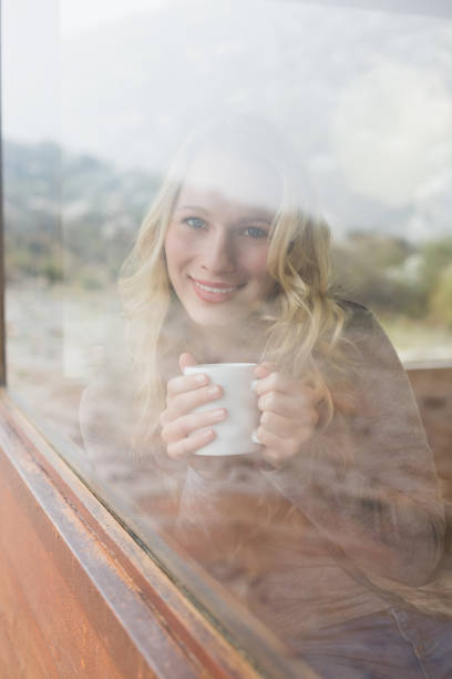 istock Content woman with coffee cup looking out through window 836357986