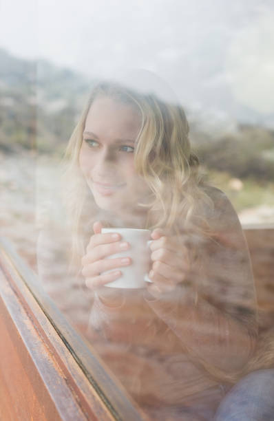 istock Thoughtful content woman with coffee cup looking out through window 836357996