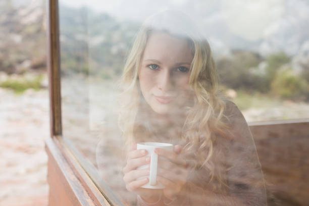 istock Content woman with coffee cup looking through window 836358072