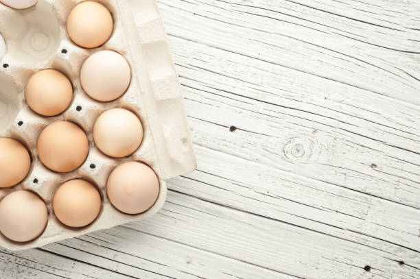 istock chicken eggs in cardboard box on white wooden background 836358560
