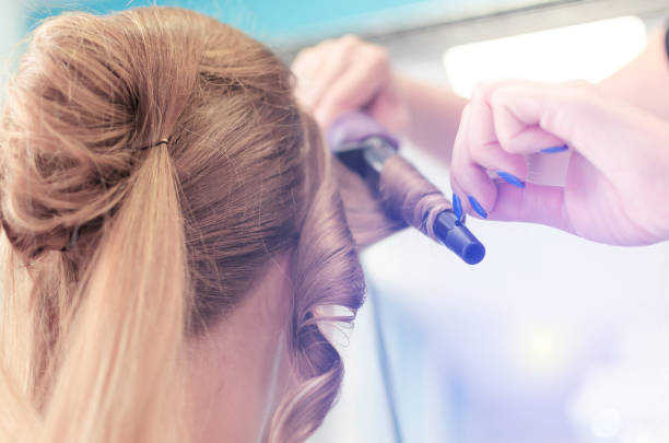 istock Stylist's hand using curling iron for hair curls 836358606