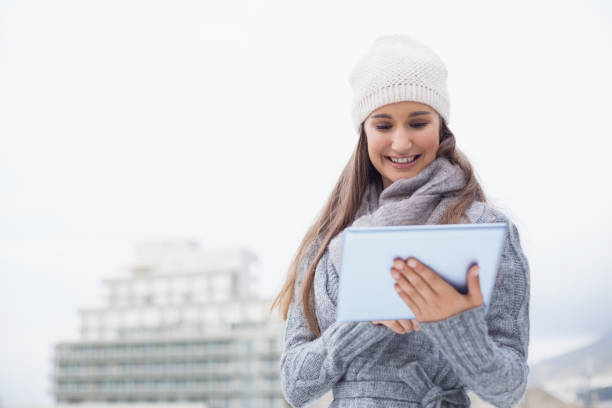 istock Smiling woman with winter clothes on using her tablet 836364496