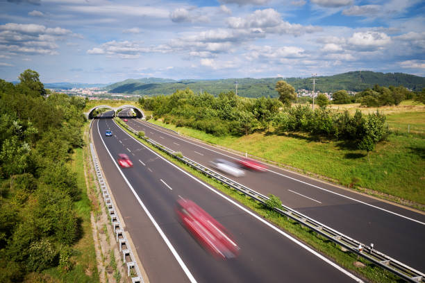 Motion blurred cars on a highway in a landscape with a city in the distance in the background. View from above.