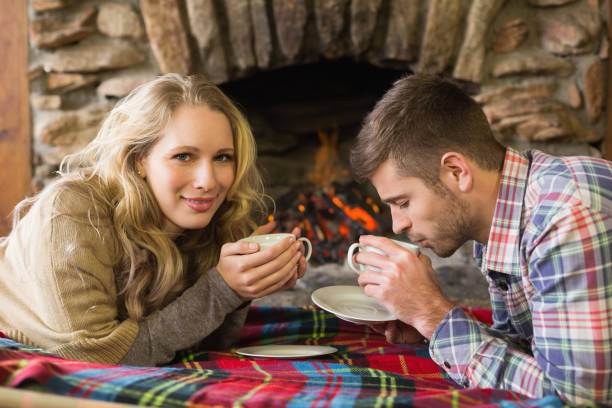 istock Couple with tea cups in front of lit fireplace 836372804