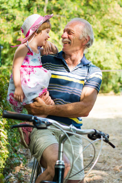 istock Grandpa laughing on bicycle with granddaughter 836373368