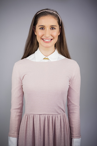 Portrait of smiling pretty model posing on grey background