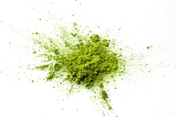 Matcha powder explosion on white background top view. Matcha is made of finely ground green tea powder. It's very common in japanese culture. Matcha is healthy due to it's high antioxydant count.