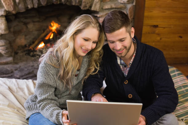 istock Couple using laptop in front of lit fireplace 836383082