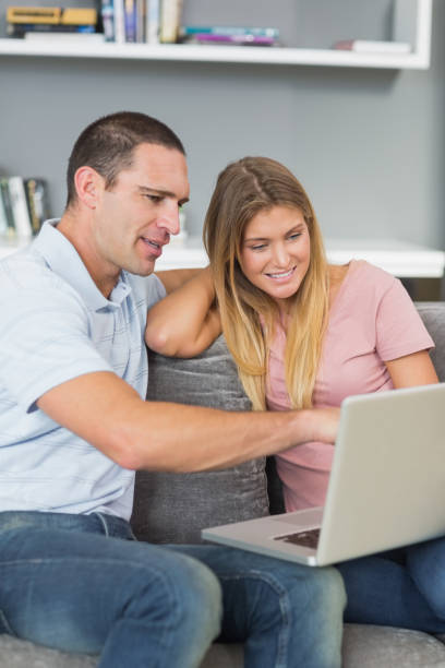 istock Cheerful couple sitting using laptop on the sofa together 836387338