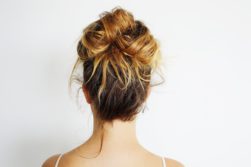 Young girl with hair piled high in a messy bun.