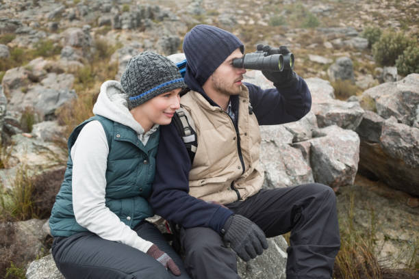 istock Couple sitting on rock with binoculars while on a hike 836391482