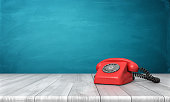 3d rendering of a bright red dial phone standing on a wooden desk and a blue wall background