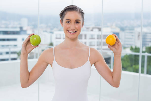 istock Cheerful sporty brunette holding apple and orange 836402570