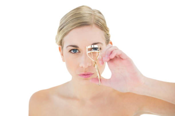 istock Concentrated young blonde woman using eyelash curler 836409622