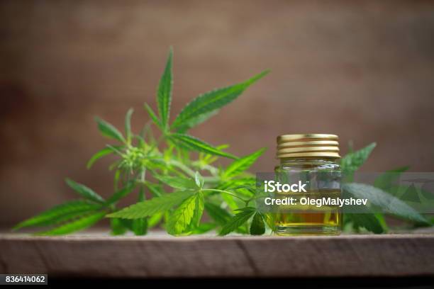 A Cannabis Leaf And A Bottle Of Hemp Oil On A Wooden Table Stock Photo - Download Image Now