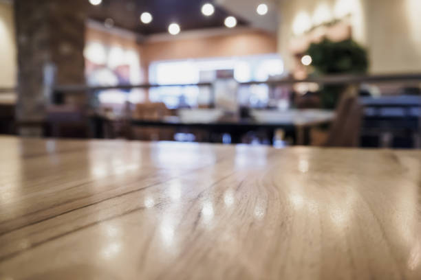 Empty wood table top with blurred cafe restaurant coffee shop interior background Empty wood table top with blurred cafe restaurant coffee shop interior background with bokeh light, for montage product display coffee table top stock pictures, royalty-free photos & images