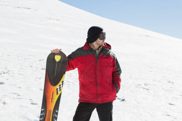 hombre con tabla de esquí mirando lejos en la nieve - clear sky diagonal snow winter fotografías e imágenes de stock