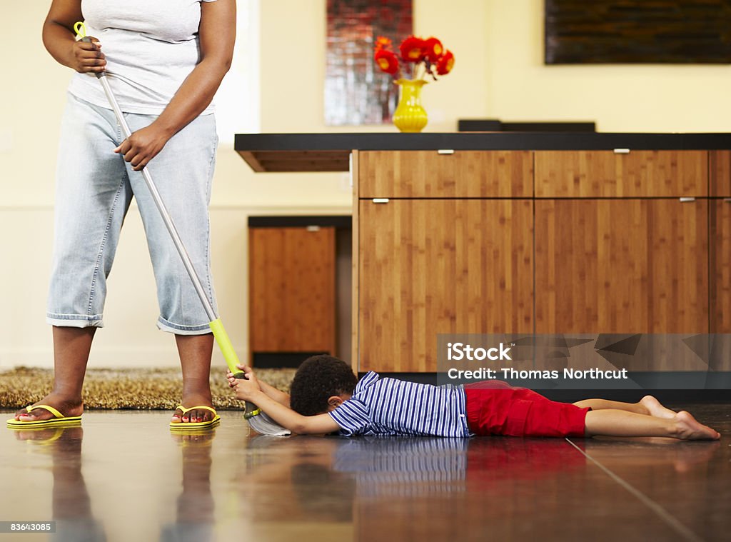 mom dragging boy across floor with broom  Child Stock Photo