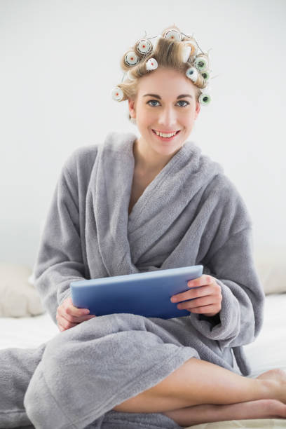 istock Pleased relaxed blonde woman in hair curlers using a tablet pc 836441012