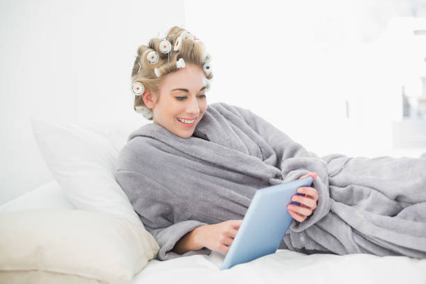 istock Charming relaxed blonde woman in hair curlers using a tablet pc 836441034
