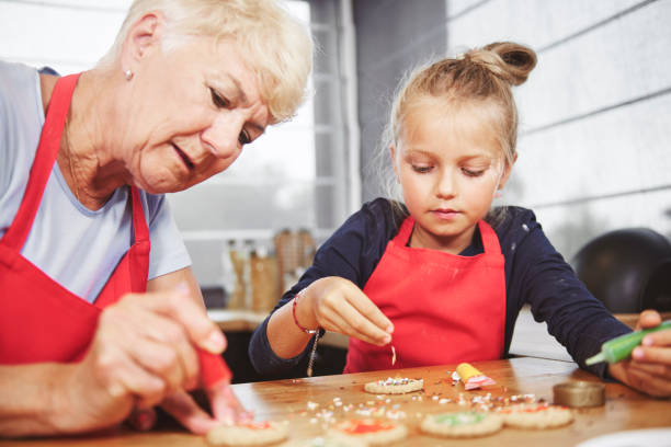 istock Grandma with girl applying icing on cookies 836445334