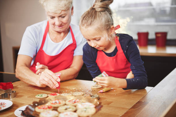 istock Grandchild with grandma decorating cookies with icing 836446620