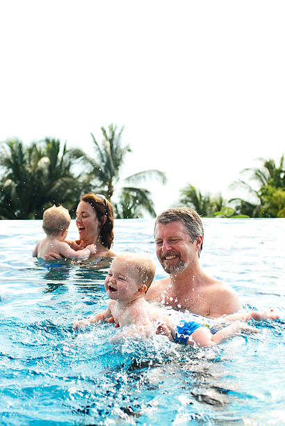 mom and dad in pool playing with toddler boy - family mouth open vertical mother zdjęcia i obrazy z banku zdjęć