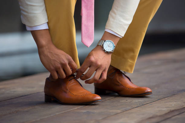 istock Well dressed man ties his brown leather shoe lace 836449822