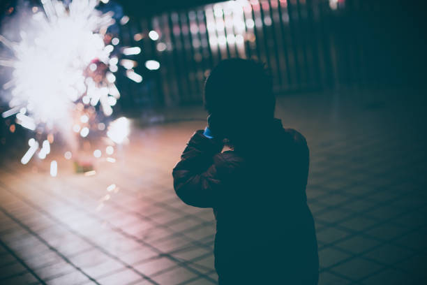 Boy looking fireworks with hands covering ears stock photo