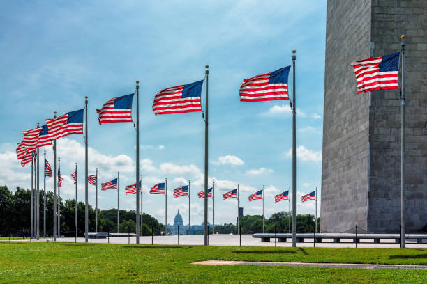 US flags near Washington Monument US flags near Washington Monument and Capitol building in background in sunny day. washington monument washington dc stock pictures, royalty-free photos & images