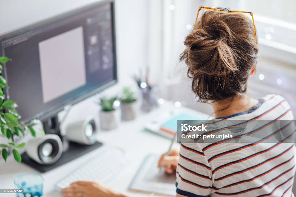 The freedom of working from home Woman in home office surrounded with digital technology working on something Rear View Stock Photo