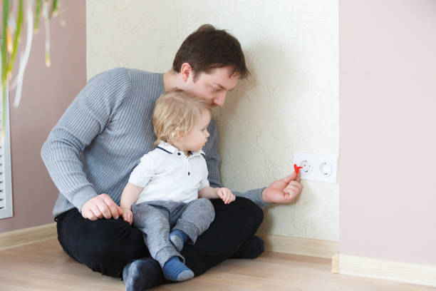 Father takes care of the safety of the child. Electrical security for safety home of ac power outlet for babies stock photo