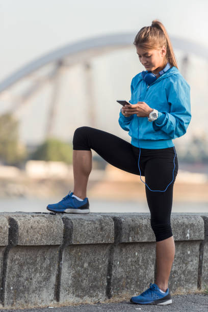 istock Young woman jogger using smart phone by the river 836505164