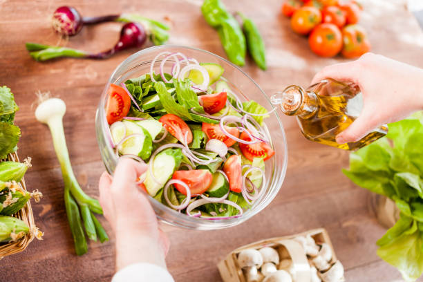 istock man pouring olive oil into healthy salad on kitchen 836518332