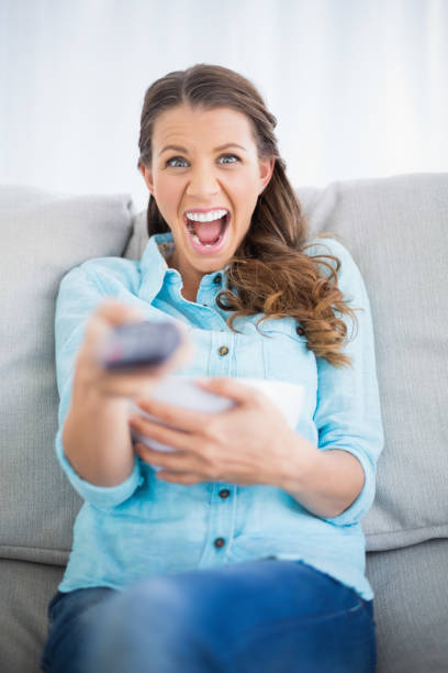 istock Woman sitting on sofa screaming while watching tv 836535732
