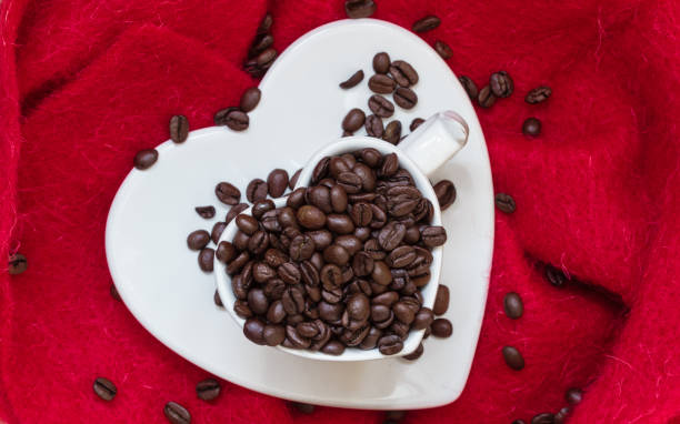 Heart shaped cup with coffee beans on red