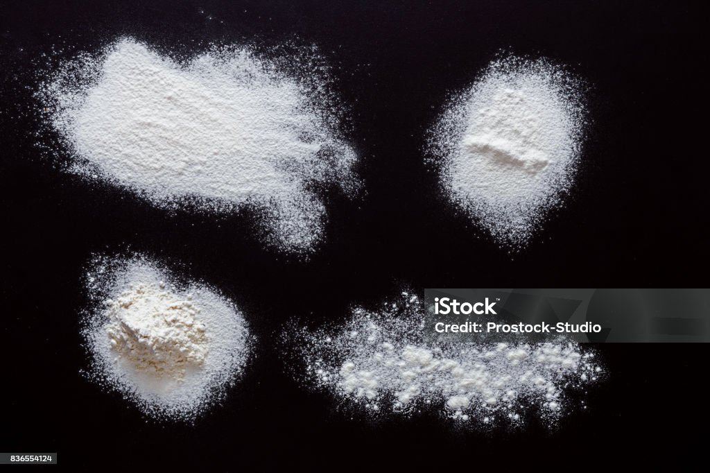 Sprinkled wheat flour splash spots on black background White flour splash spots on black background. Top view on blackboard. Baking concept, cooking dough or pastry. Flour Stock Photo