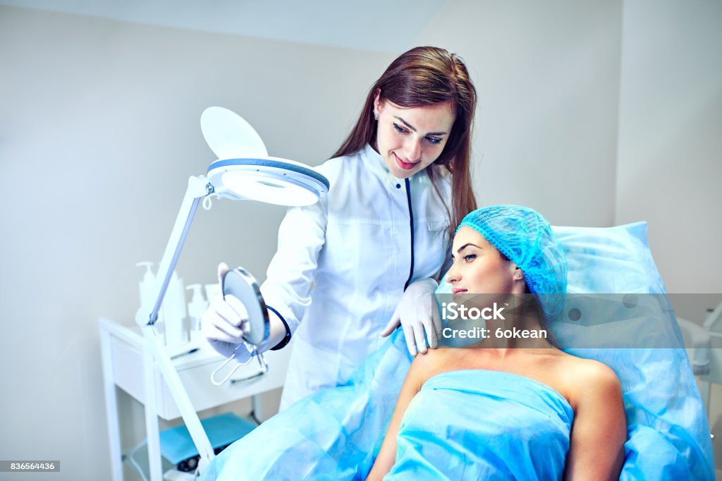 The cosmetologist is caring for the patient's face A woman cosmetologist at work in the hospital Patient Stock Photo
