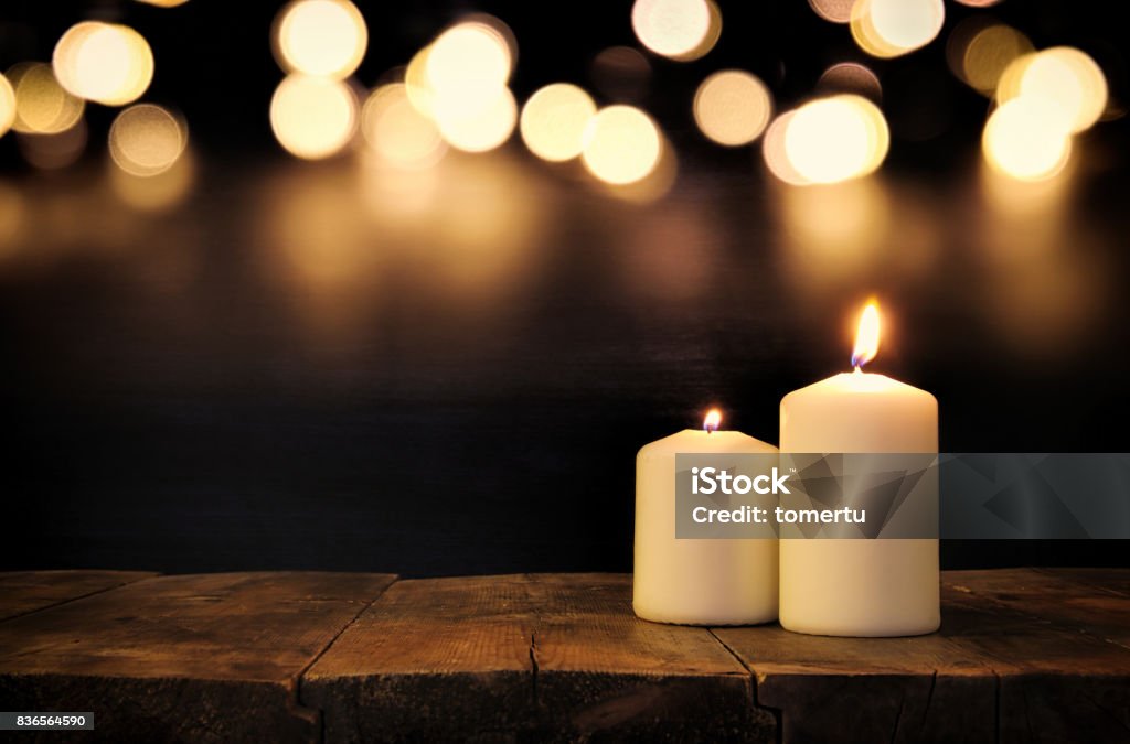 Burning candles over old wooden table with bokeh lights Burning candles over old wooden table with bokeh lights. Candle Stock Photo