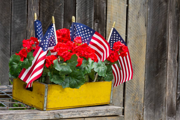 American Flags and Red Geraniums in yellow wood crate